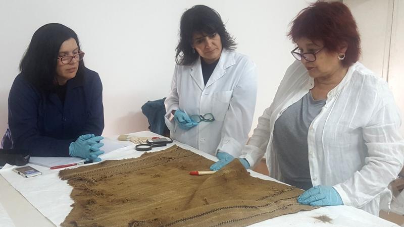 Resultado de Análisis de Textiles asociados a Momias chilenas serán expuestos en el MHNV Marinella Bustamante, Patricia Günther , Ana María Iglesias investigadoras de la escuela de Diseño de la Universidad de Valparaíso realizando estudio de Unku asociado a momia cultura Arica, colección arqueológica Chile-Momia del Museo de Historia Natura